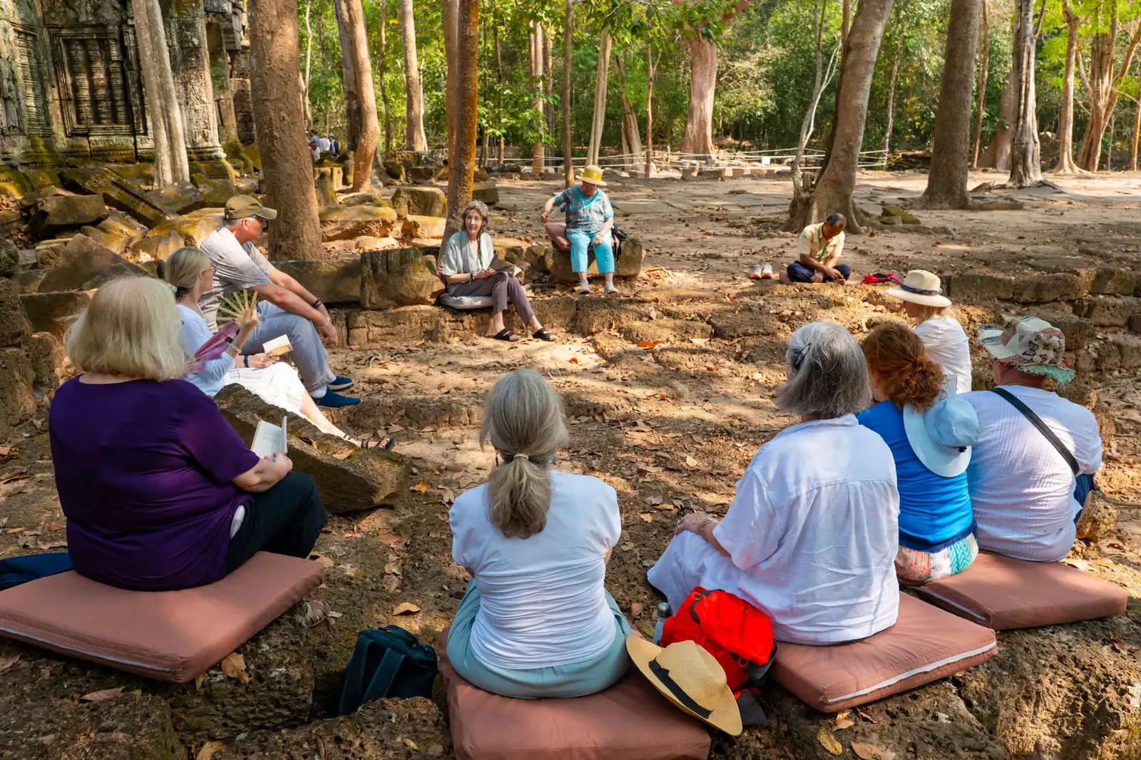 Susan teaching the retreat group at temple ruins outdoors - Cambodia